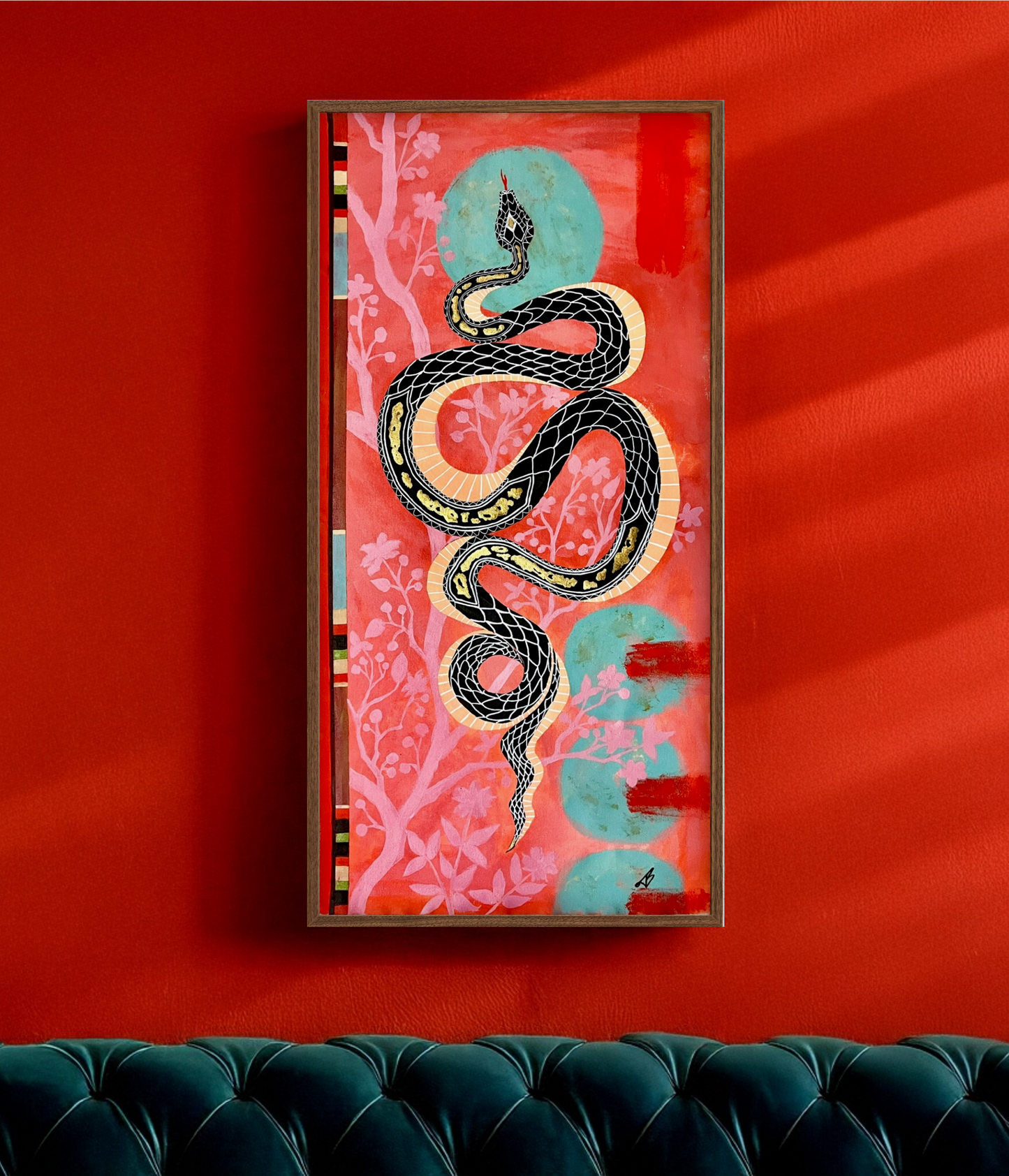 Framed artwork with a snake design on a red wall above a green sofa.
