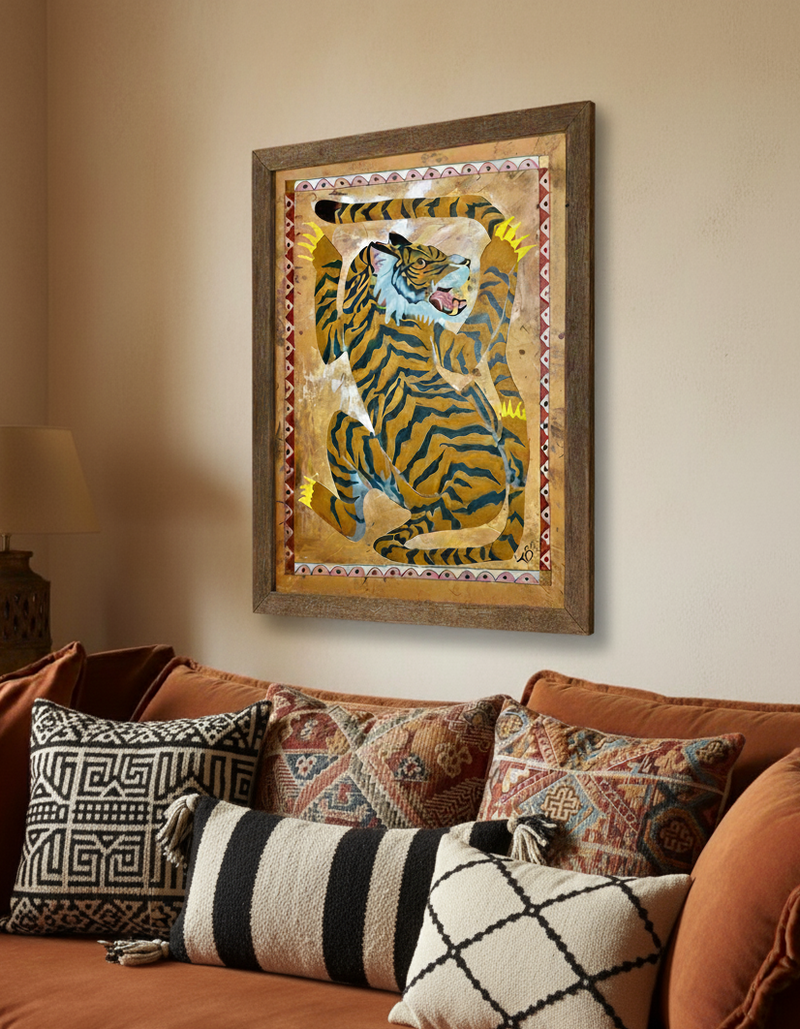Framed artwork of a tiger on a wall above a brown sofa with patterned cushions.